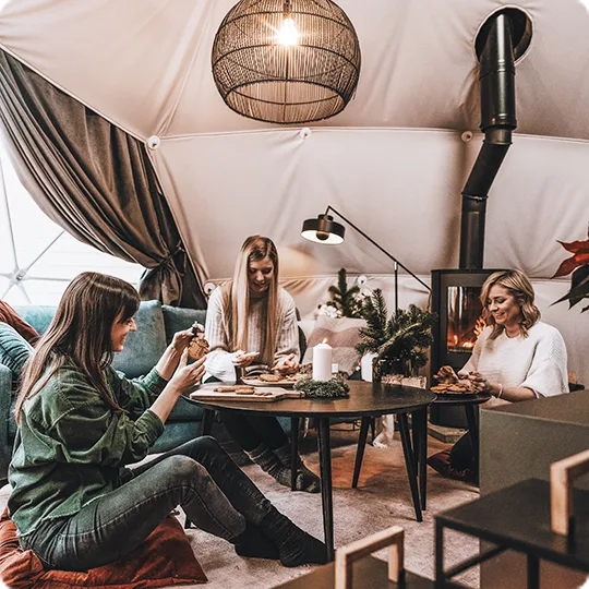 trzy kobiety spędzają czas w przytulnym wnętrzu geodezyjnej kopuły